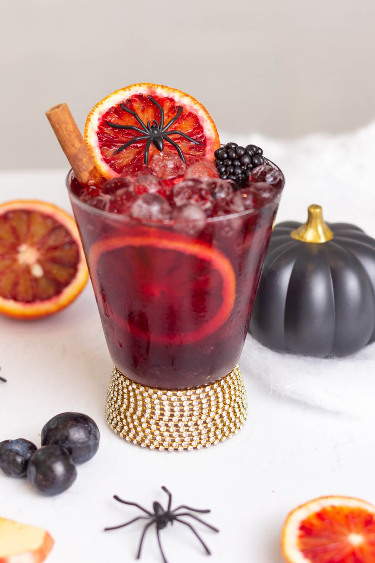 tumbler glass with a diamante base with red Halloween themed liquid and garnishes inside.