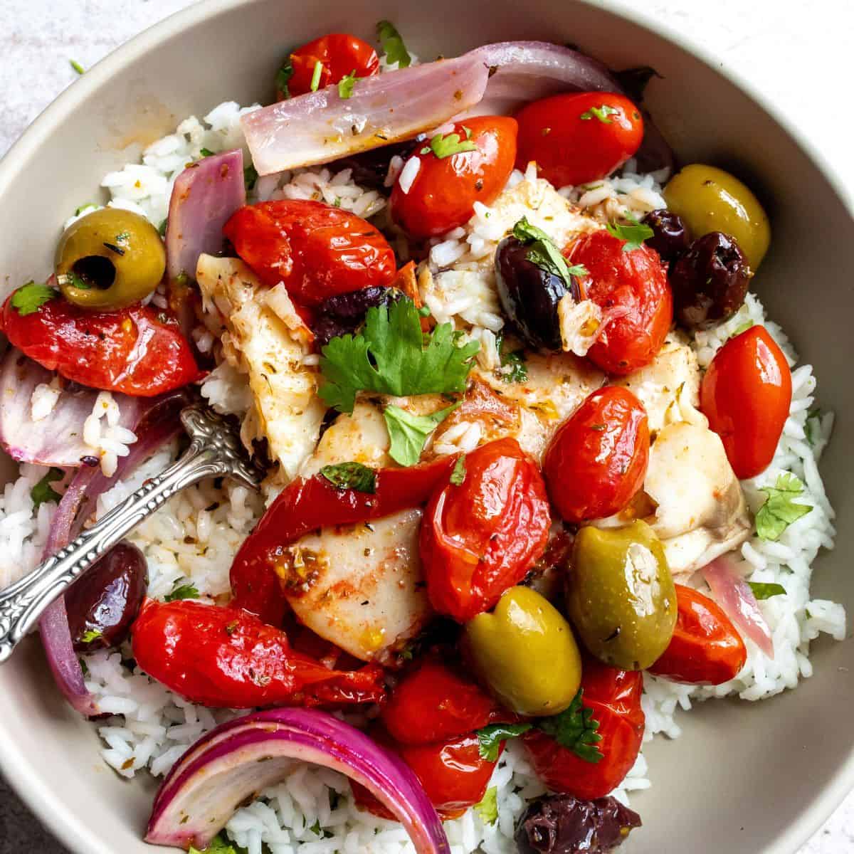 Mediterranean baked white fish served over rice in a bowl. 